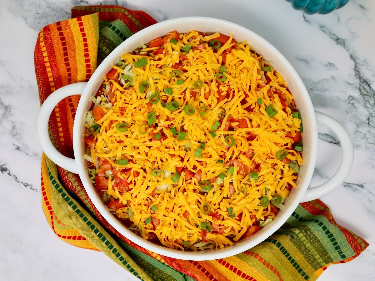 a mexican layer dip topped with shredded cheese and green onions