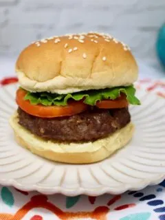 an air fryer hamburger topped with lettuce and sliced tomatoes