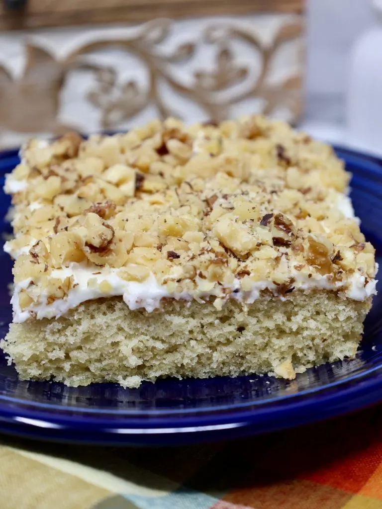 banana cake with cream cheese frosting topped with toasted nuts