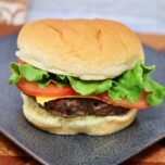 a hamburger that was baked in the oven topped wtih lettuce tomatoes, and cheese