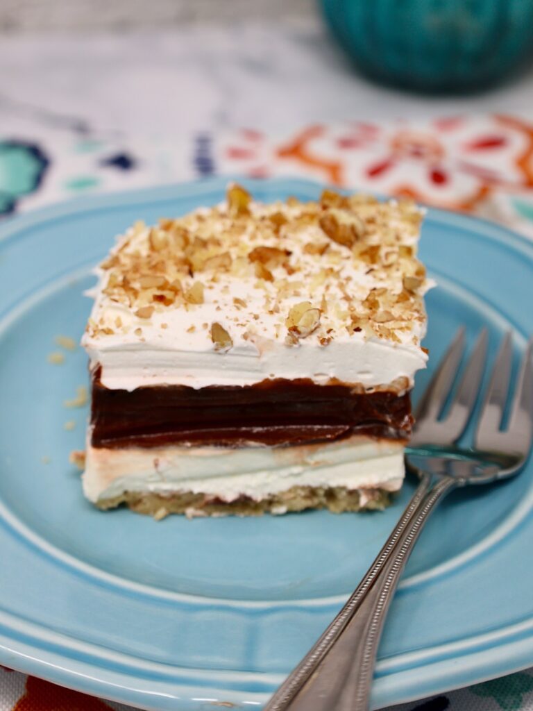 a beautiful slice of four layer delight dessert lasagna with a fork reading to eat