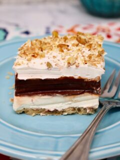 a slice of four layer delight on a blue plate with a fork beside it