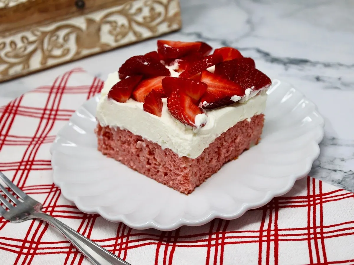 strawberry cream cake on a white ruffled plate