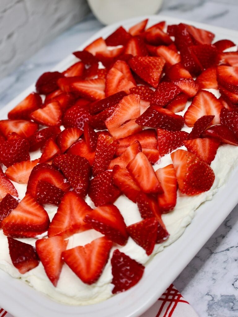 a pan of strawberry cream cake with loads of fresh strawberries and cream