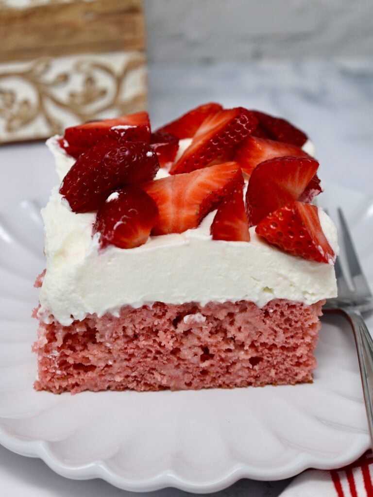 slice of strawberries and cream cake with a fork beside it 