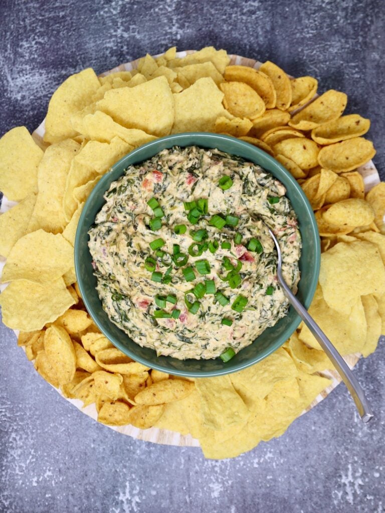 fiesta cheese dip with spinach surrounded by tortilla chips