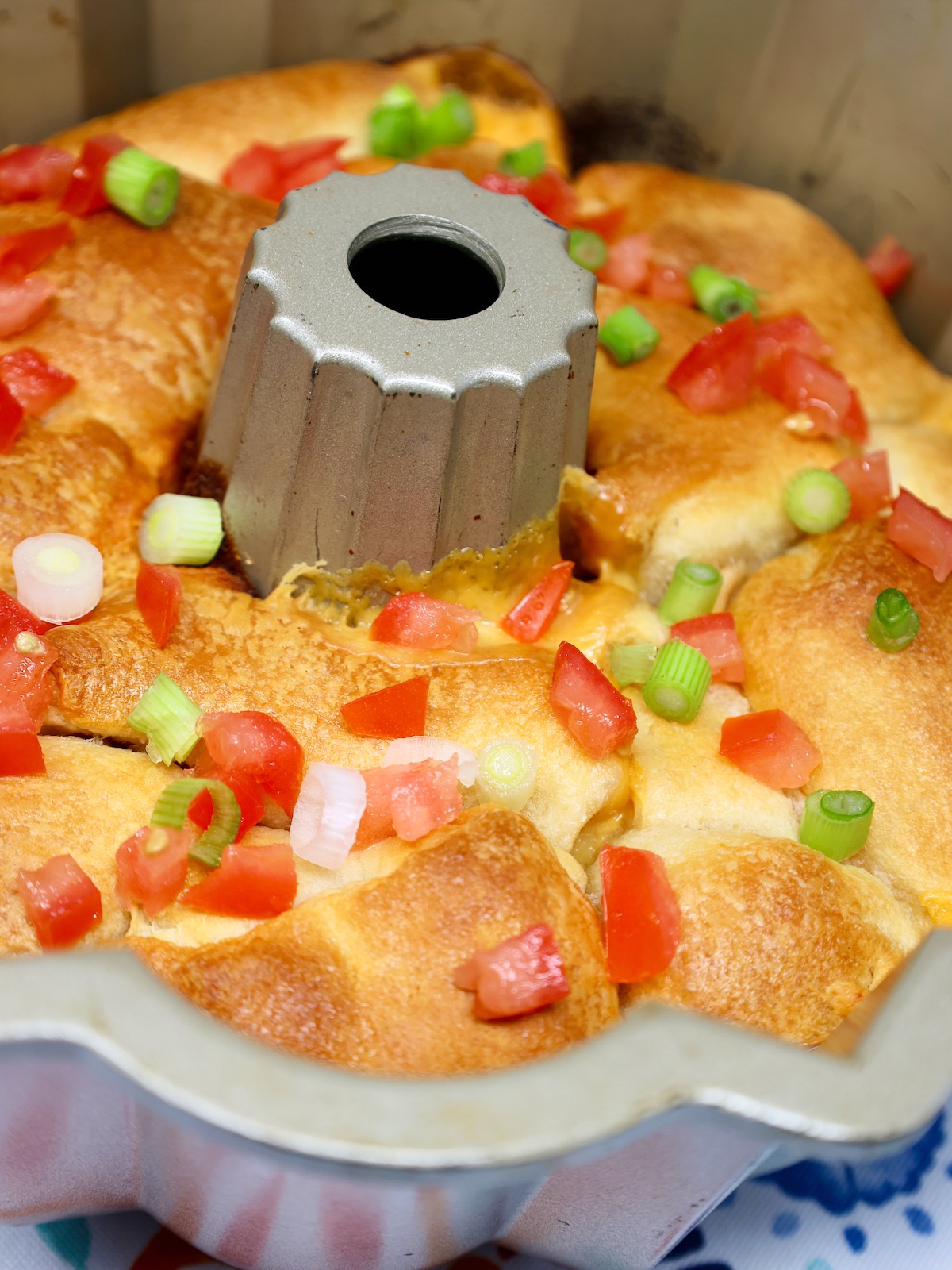 pull apart queso monkey bread in a bundt pan garnished with tomatoes and green onions