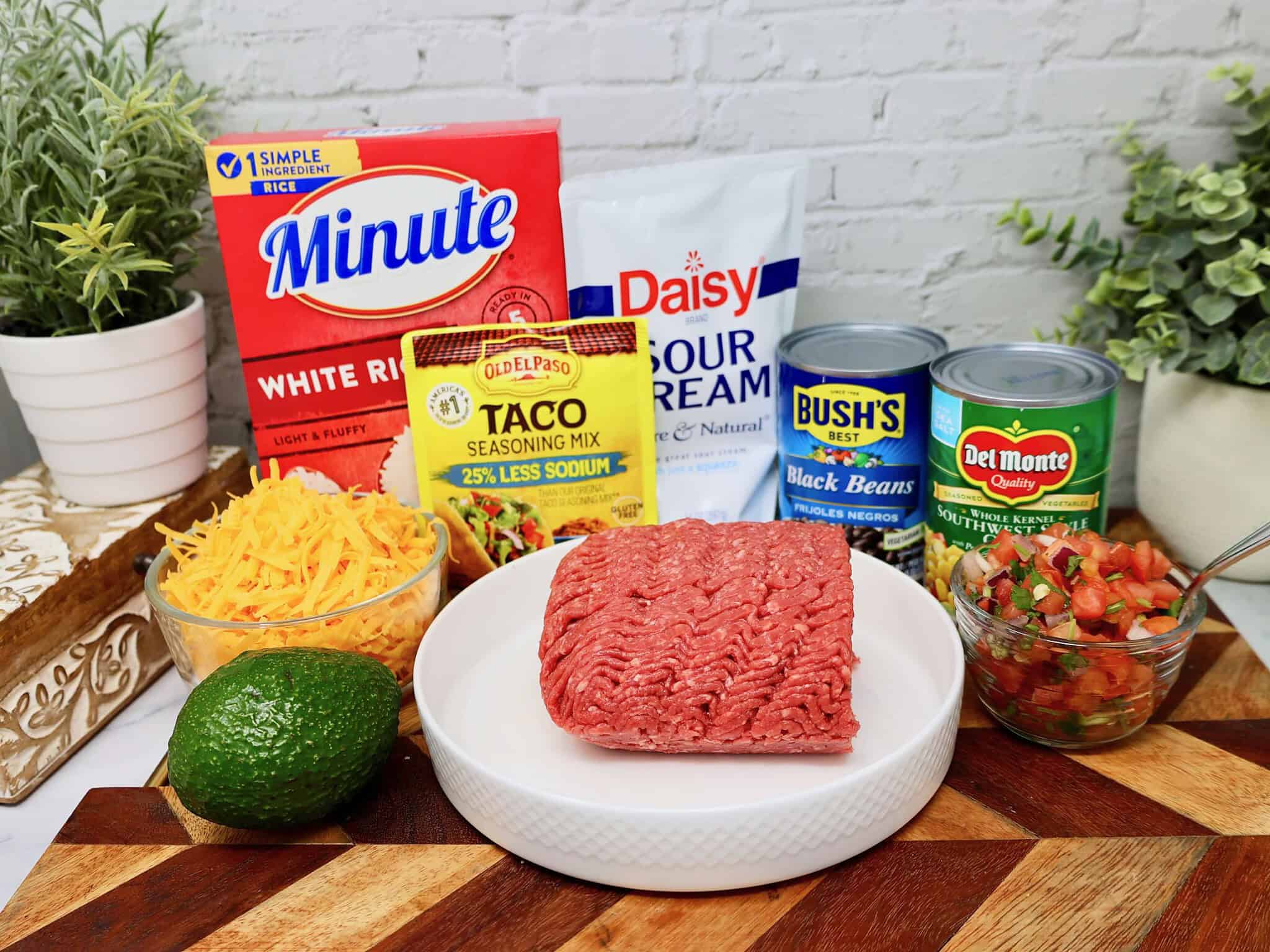Taco bowl toppings including black beans, corn, shredded cheese, lettuce, and diced tomatoes