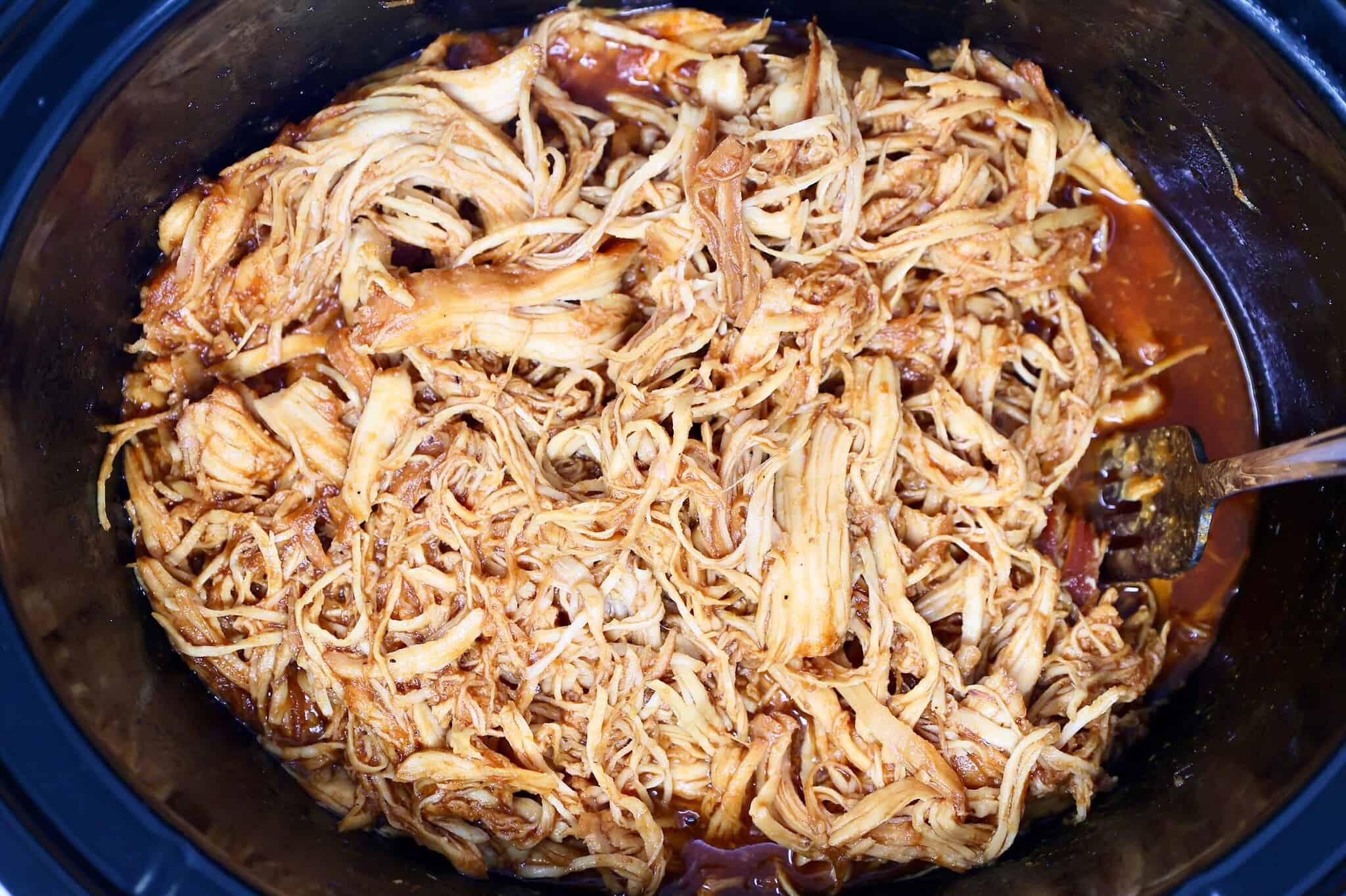 Crockpot BBQ chicken cooking in slow cooker with barbecue sauce