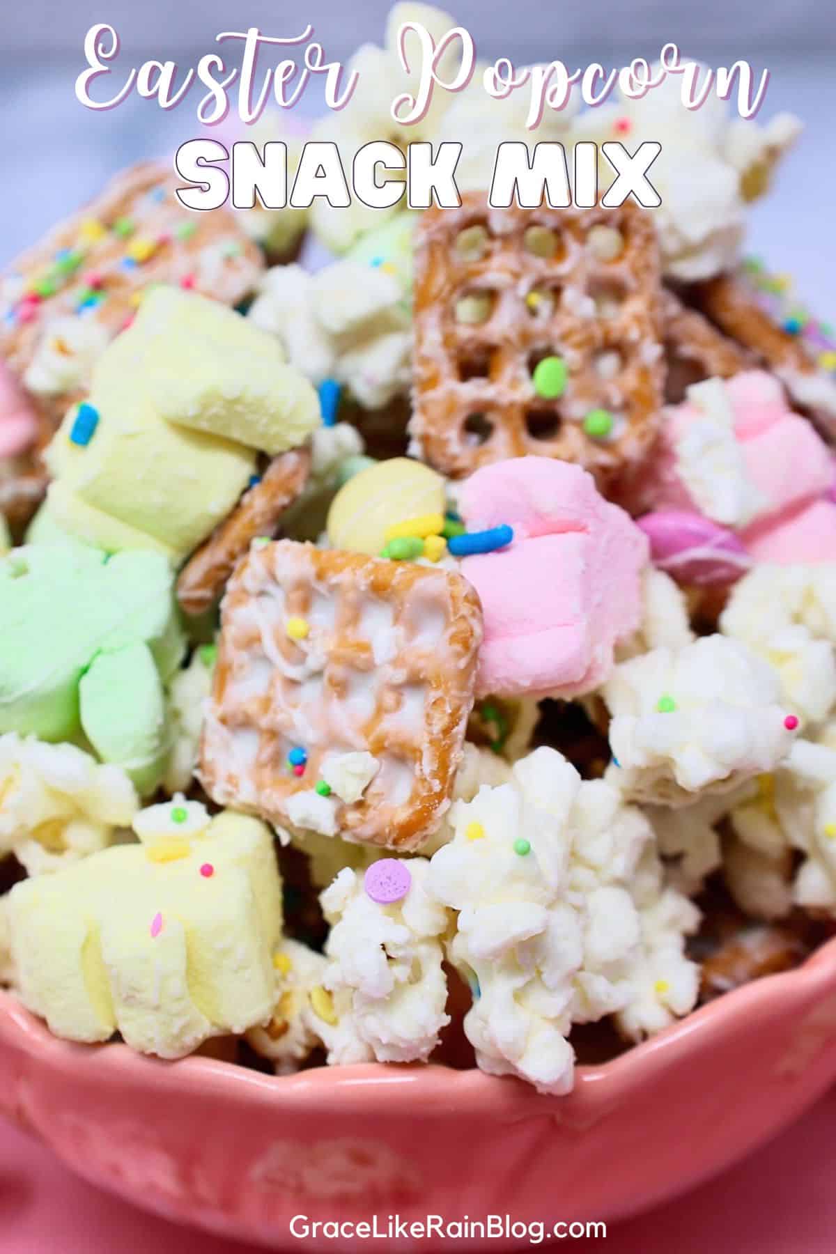 Easter popcorn snack mix in a bowl with pastel M&Ms, pretzels, marshmallows, and white chocolate drizzle