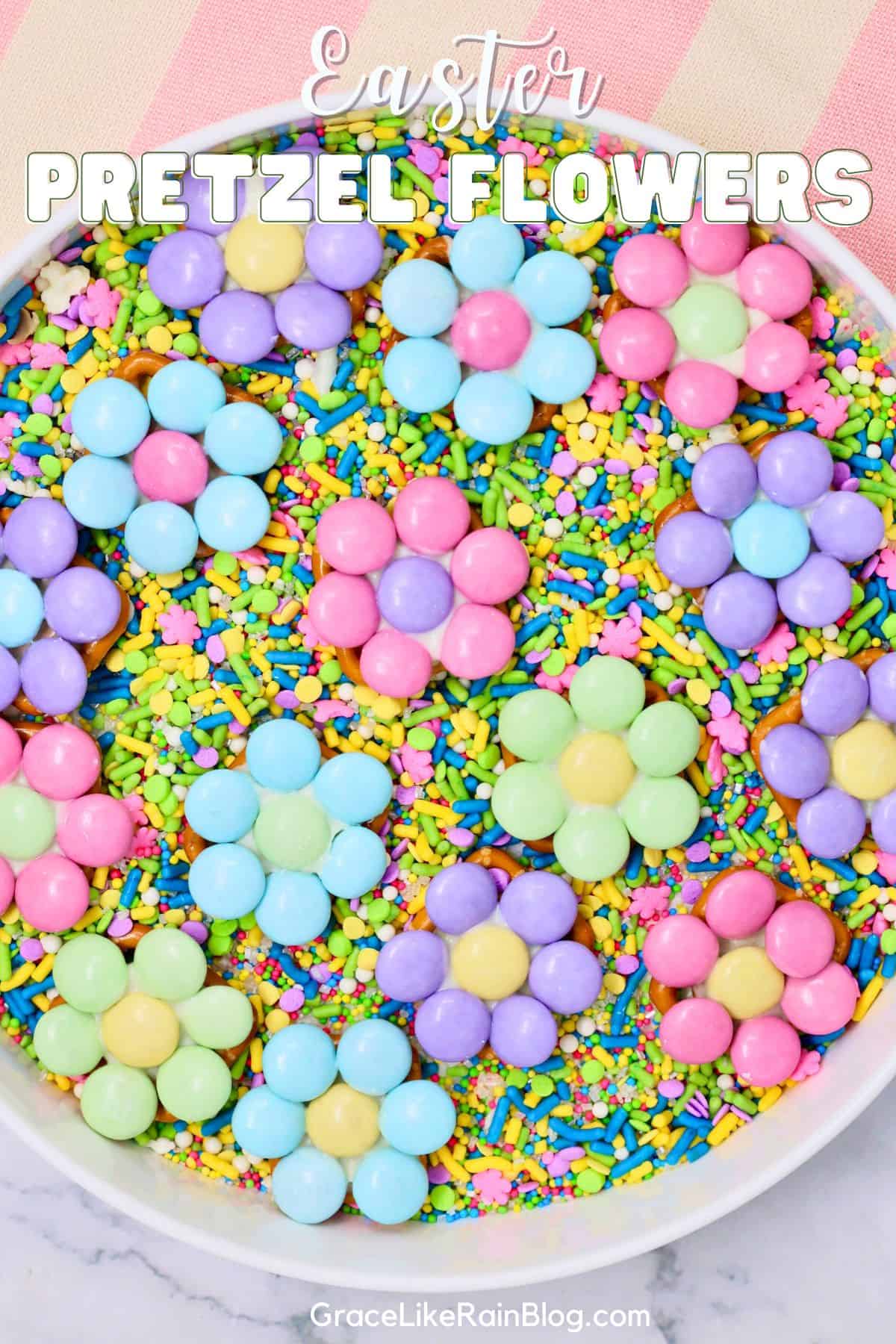 Easter pretzel flowers made with candy melts and pastel M&Ms on a white platter