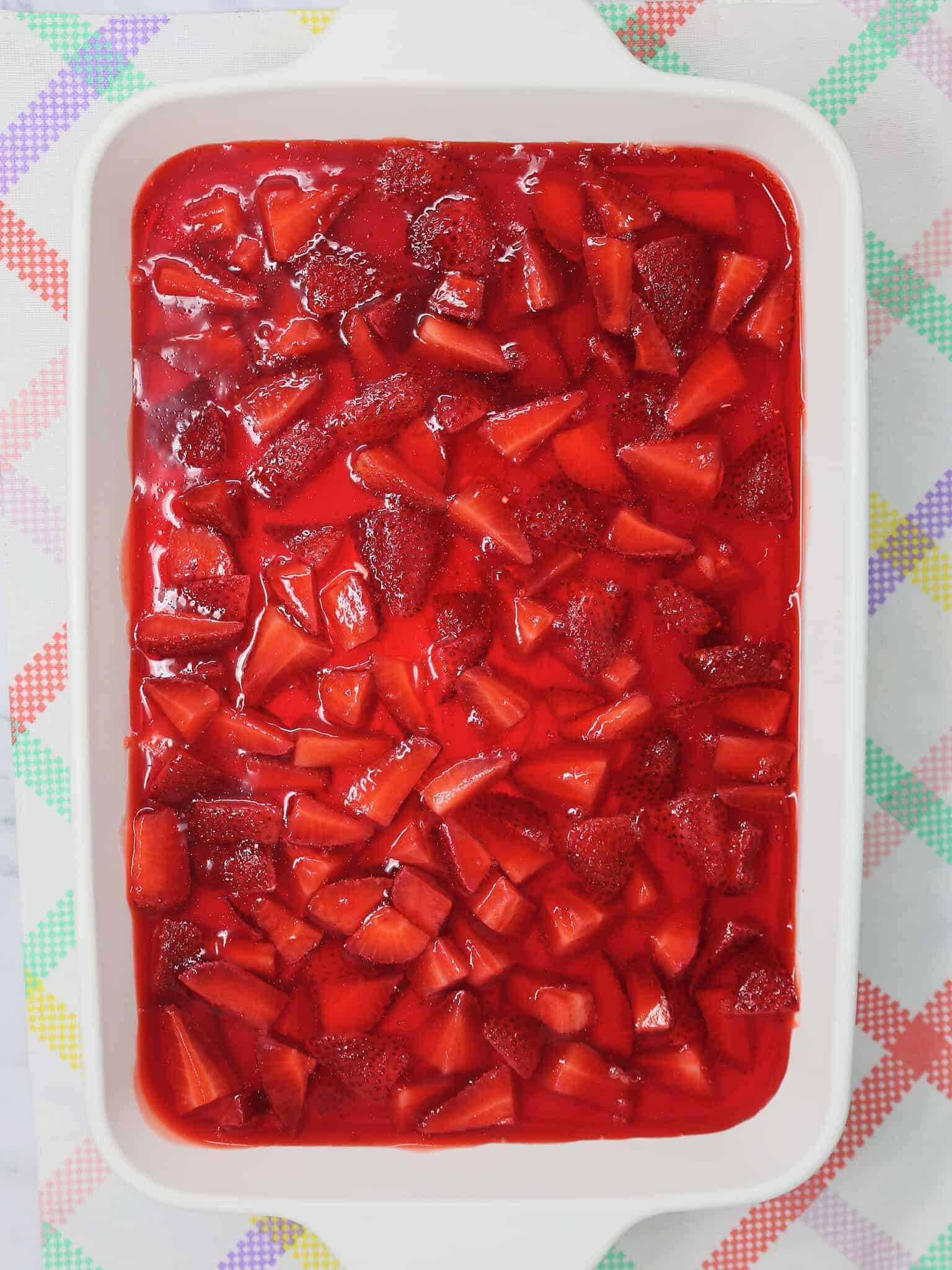 Overhead view of homemade strawberry pretzel salad in a 9x13 dish ready to serve at a potluck