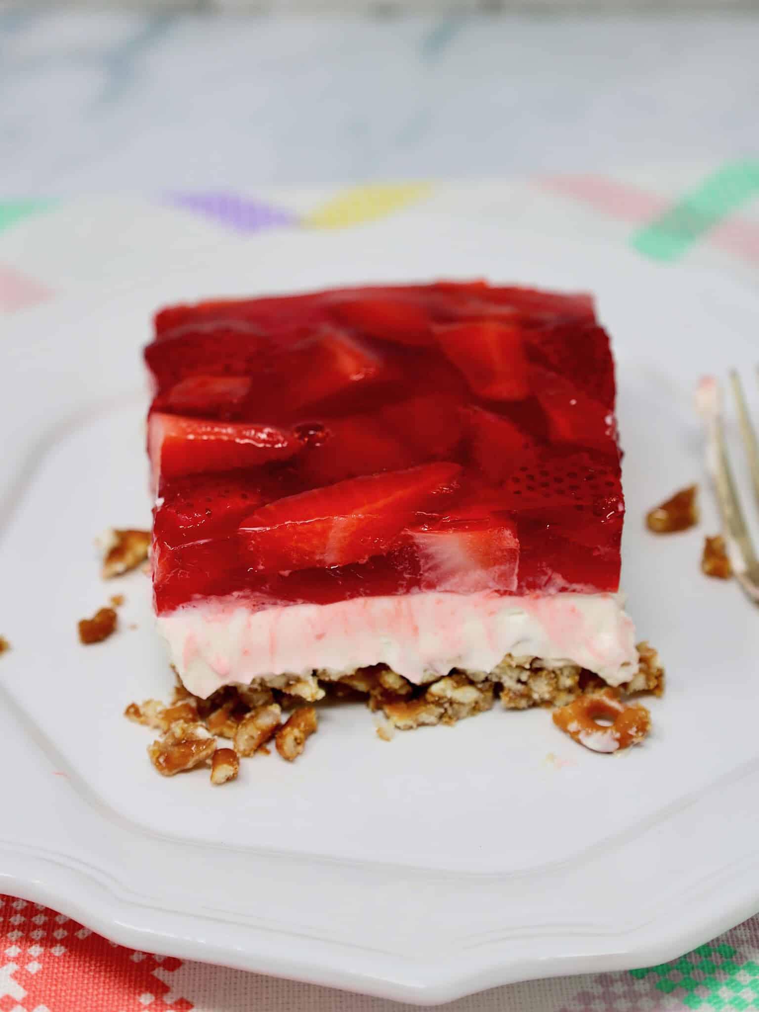 Slice of strawberry pretzel salad showing layers of pretzel crust, cream cheese filling, and strawberry gelatin topping