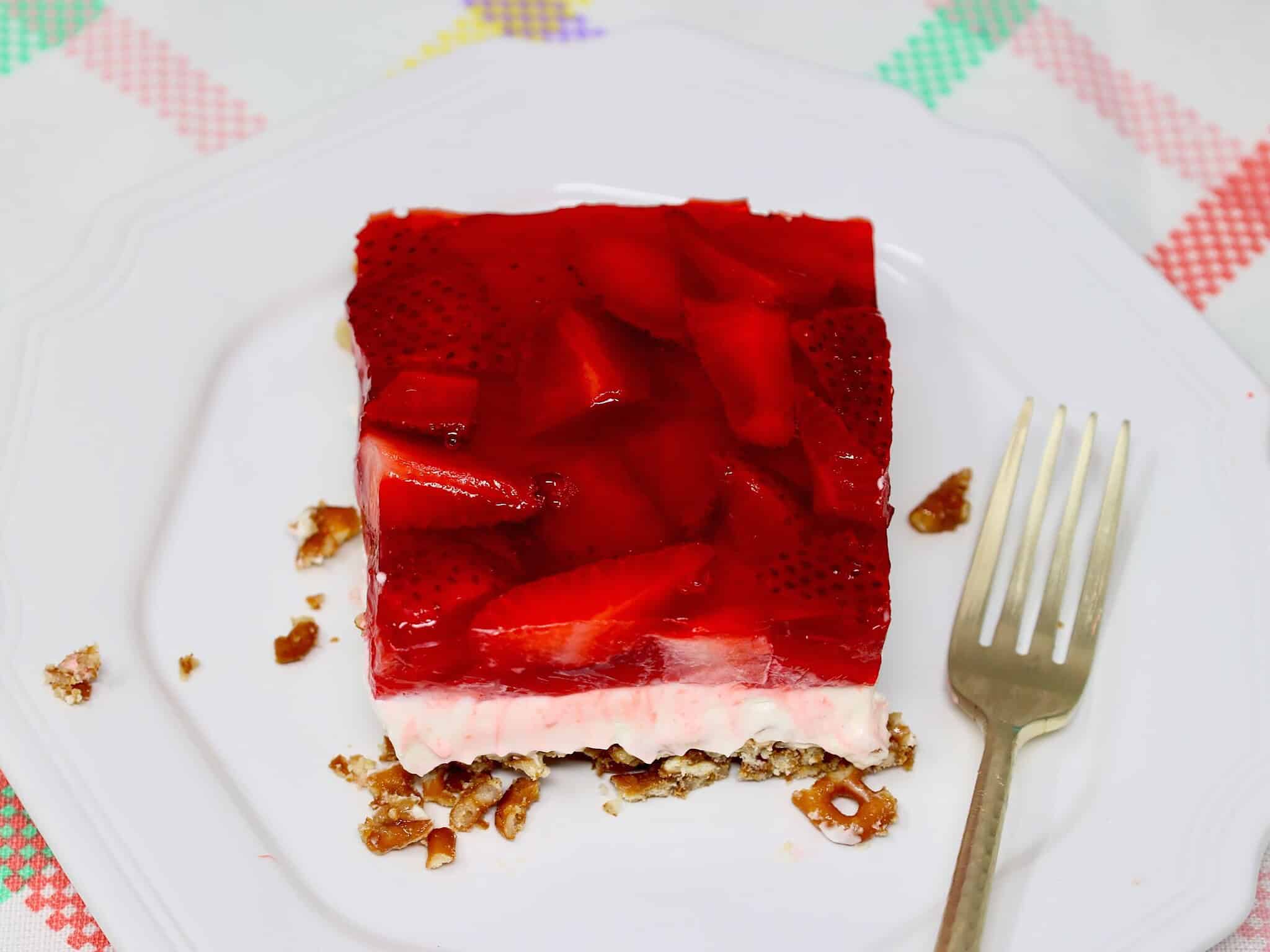 Close-up of strawberry pretzel dessert highlighting the creamy middle layer and fresh strawberry topping