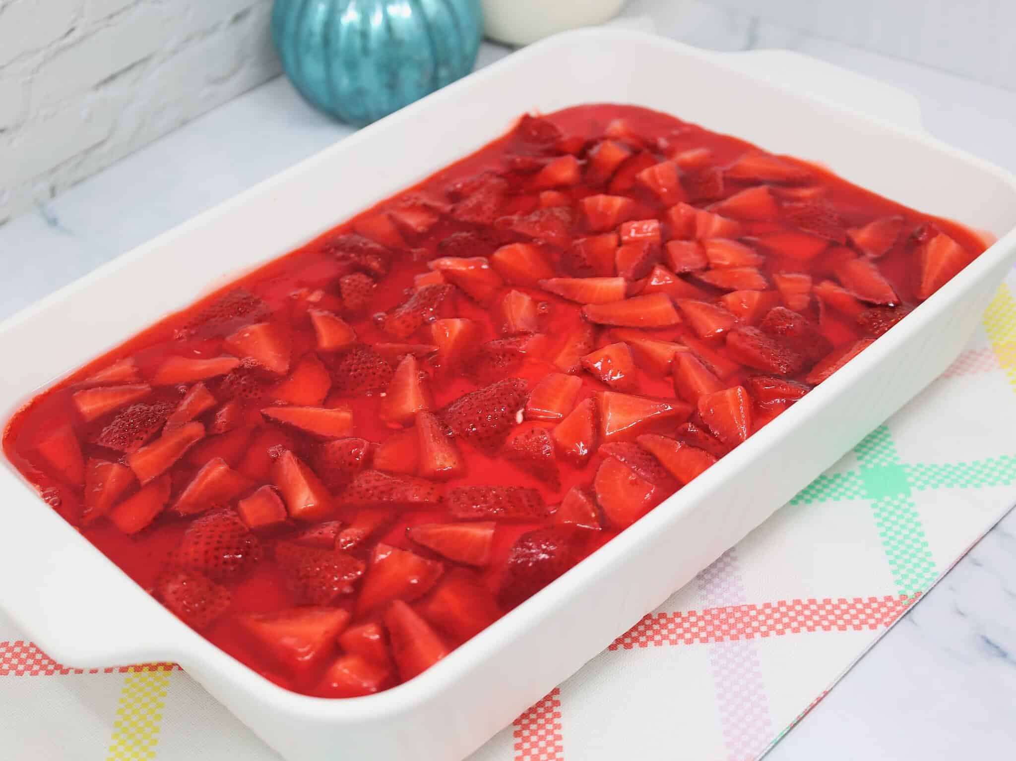 Unchilled strawberry pretzel salad with fresh strawberry topping before setting in refrigerator