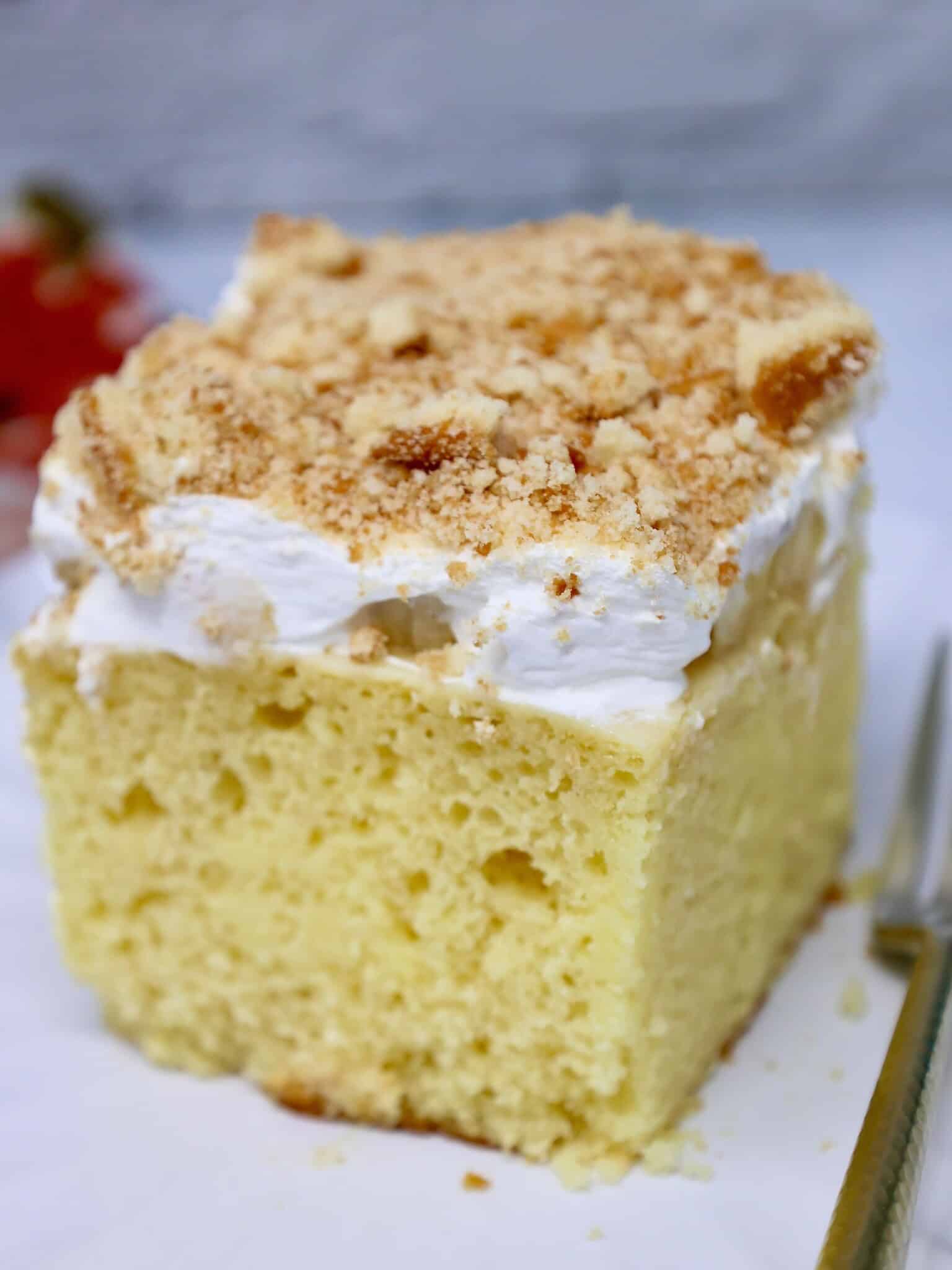 A slice of moist banana pudding cake with condensed milk showing the yellow cake layers filled with creamy banana pudding.