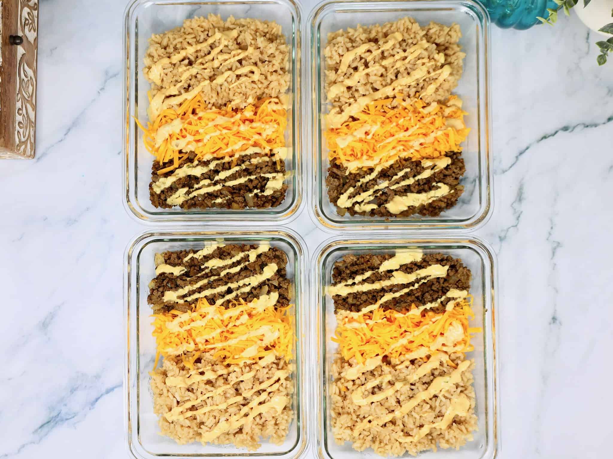 Cheeseburger meal prep bowls with rice, ground beef, cheddar cheese, and fresh burger toppings