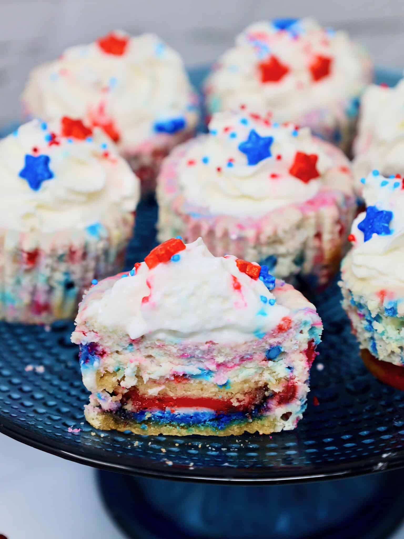 Close up of patriotic mini cheesecake with whipped cream, fresh berries, and colorful sprinkles
