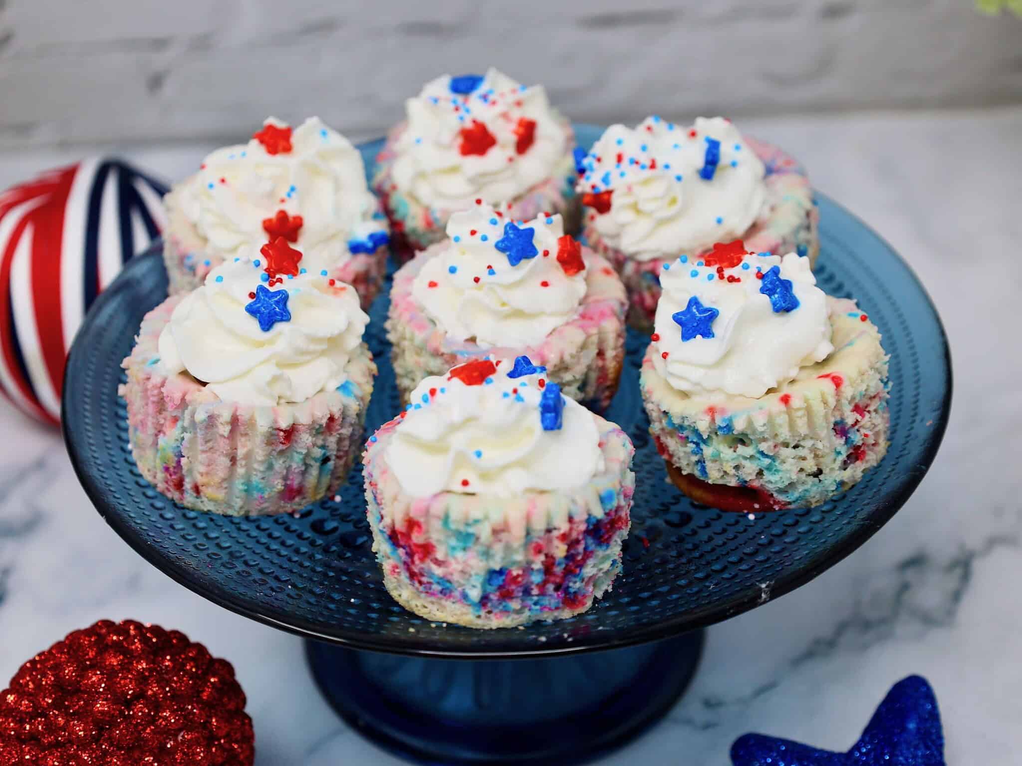 4th of July mini cheesecakes topped with whipped cream, blueberries, strawberries, and patriotic sprinkles
