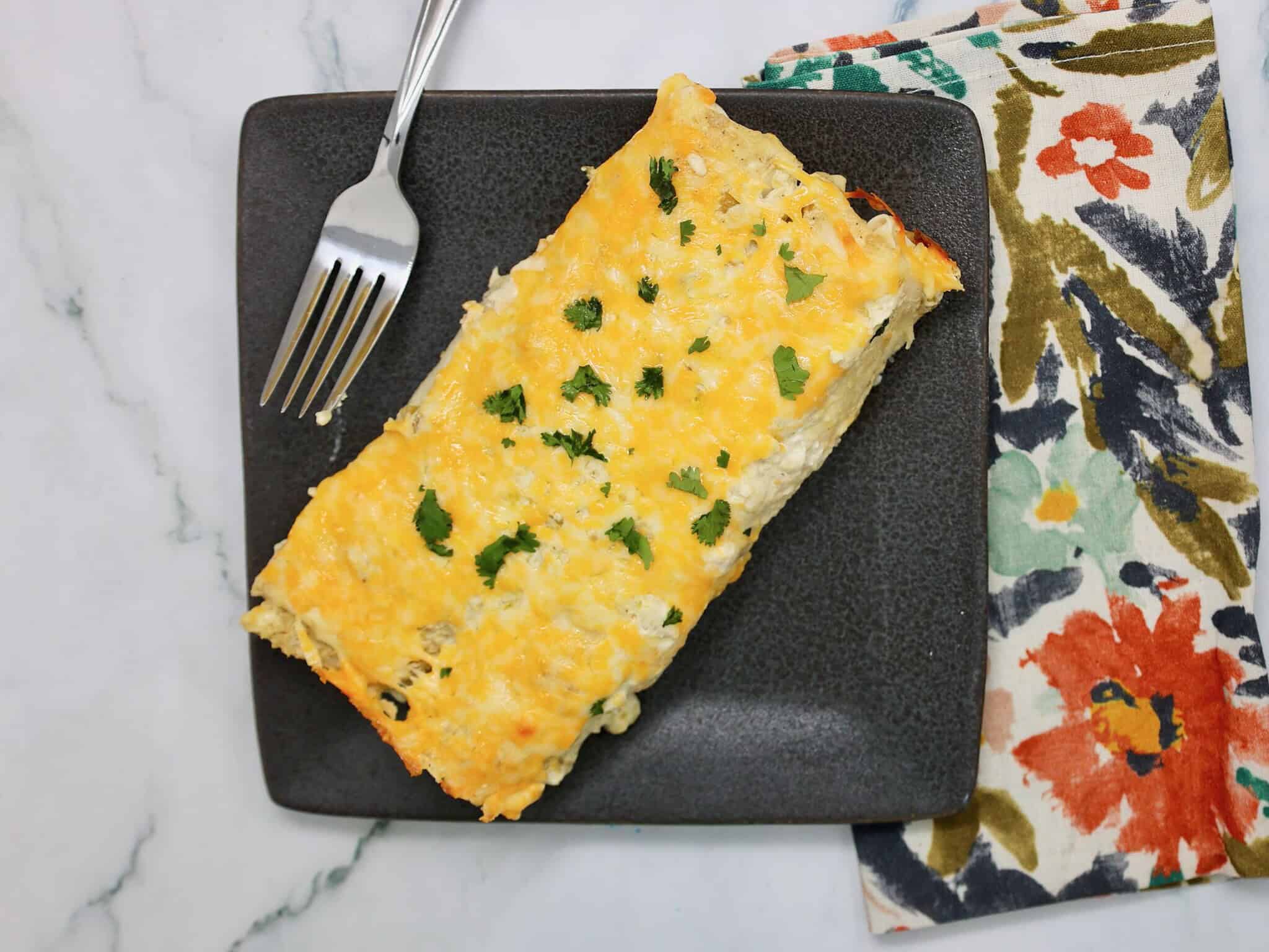 Cheesy chicken enchilada topped with salsa verde sauce and cilantro