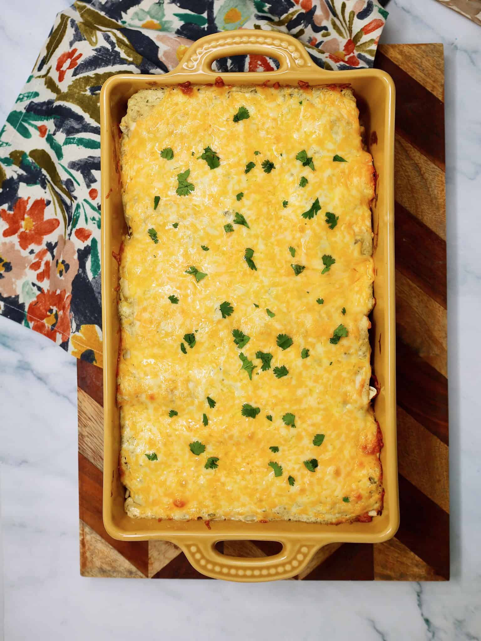 Cheesy salsa verde chicken enchiladas fresh from the oven in a baking dish