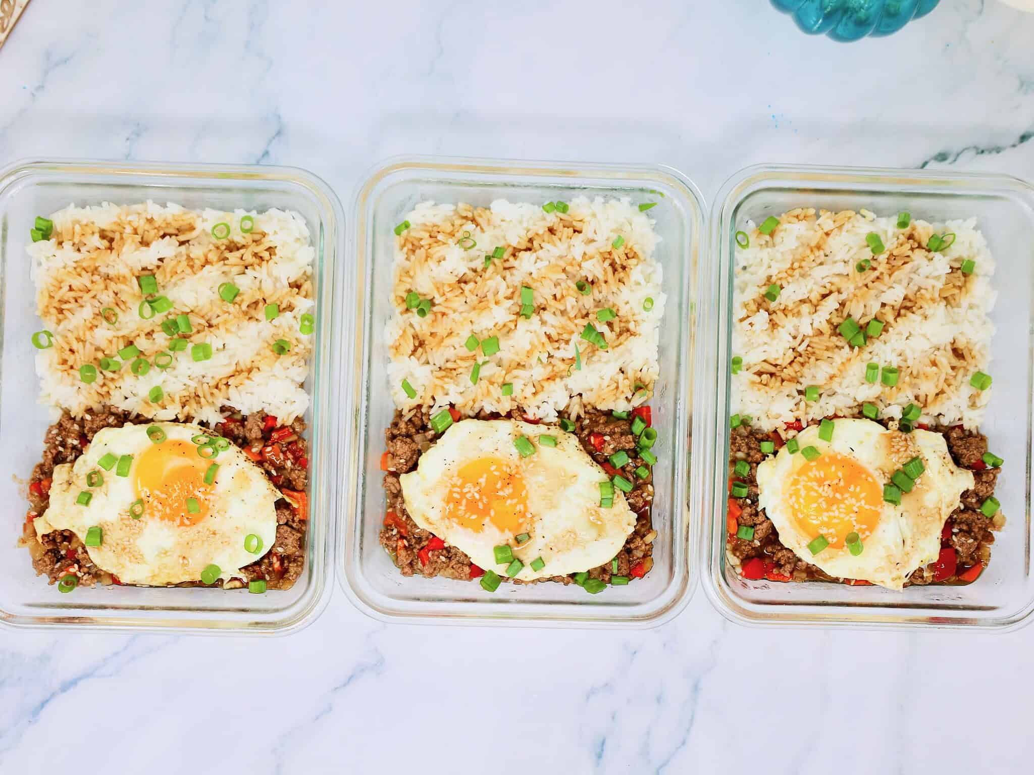 three teriyaki ground beef rice bowls arranged in glass meal prep containers ready for the week