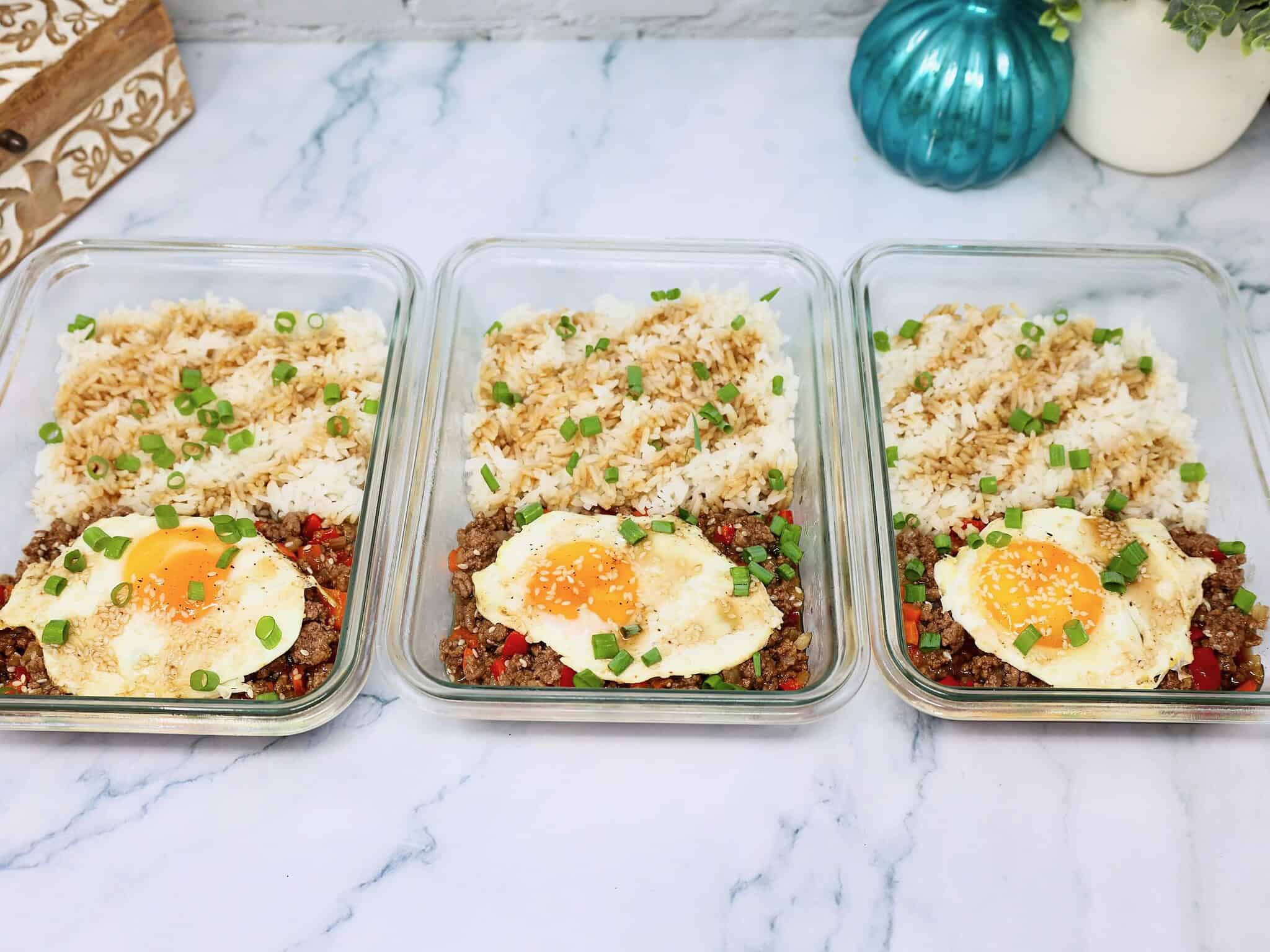 Cooked jasmine rice being portioned into meal prep containers for teriyaki beef bowls