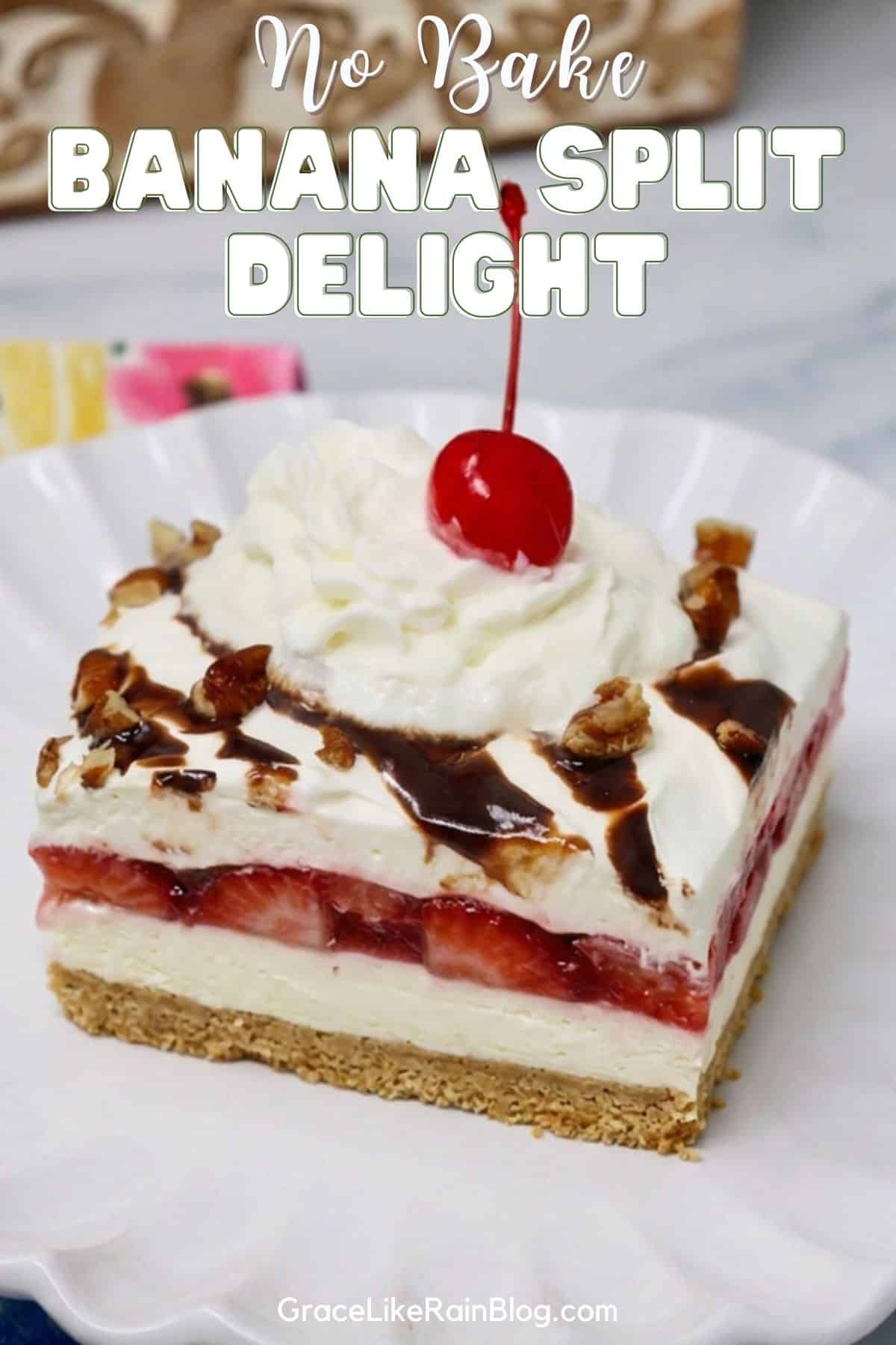 No Bake Banana Split Delight topped with chocolate syrup, whipped topping, strawberries, and maraschino cherries