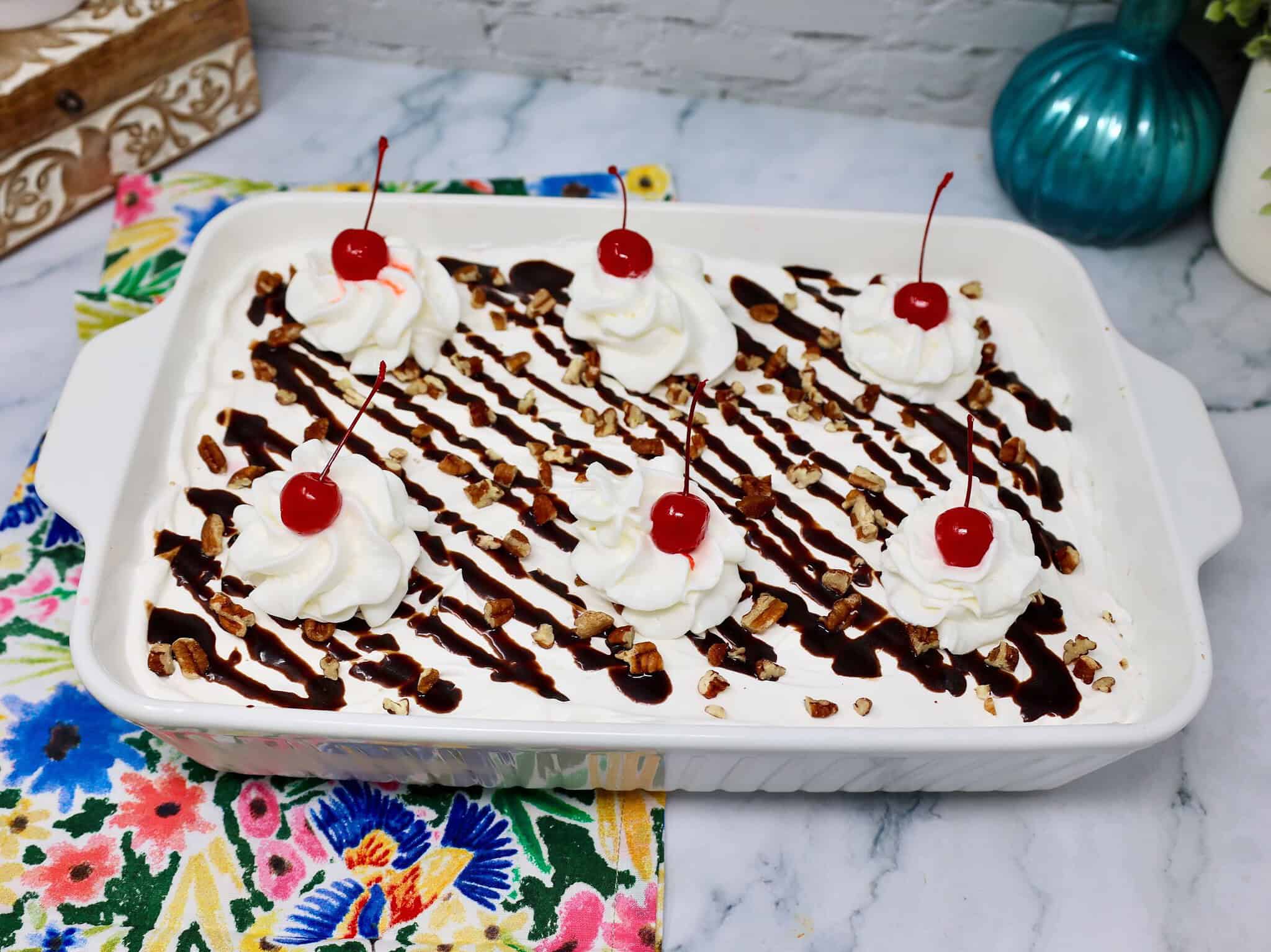 No bake strawberry banana dessert finished with chocolate drizzle and maraschino cherries