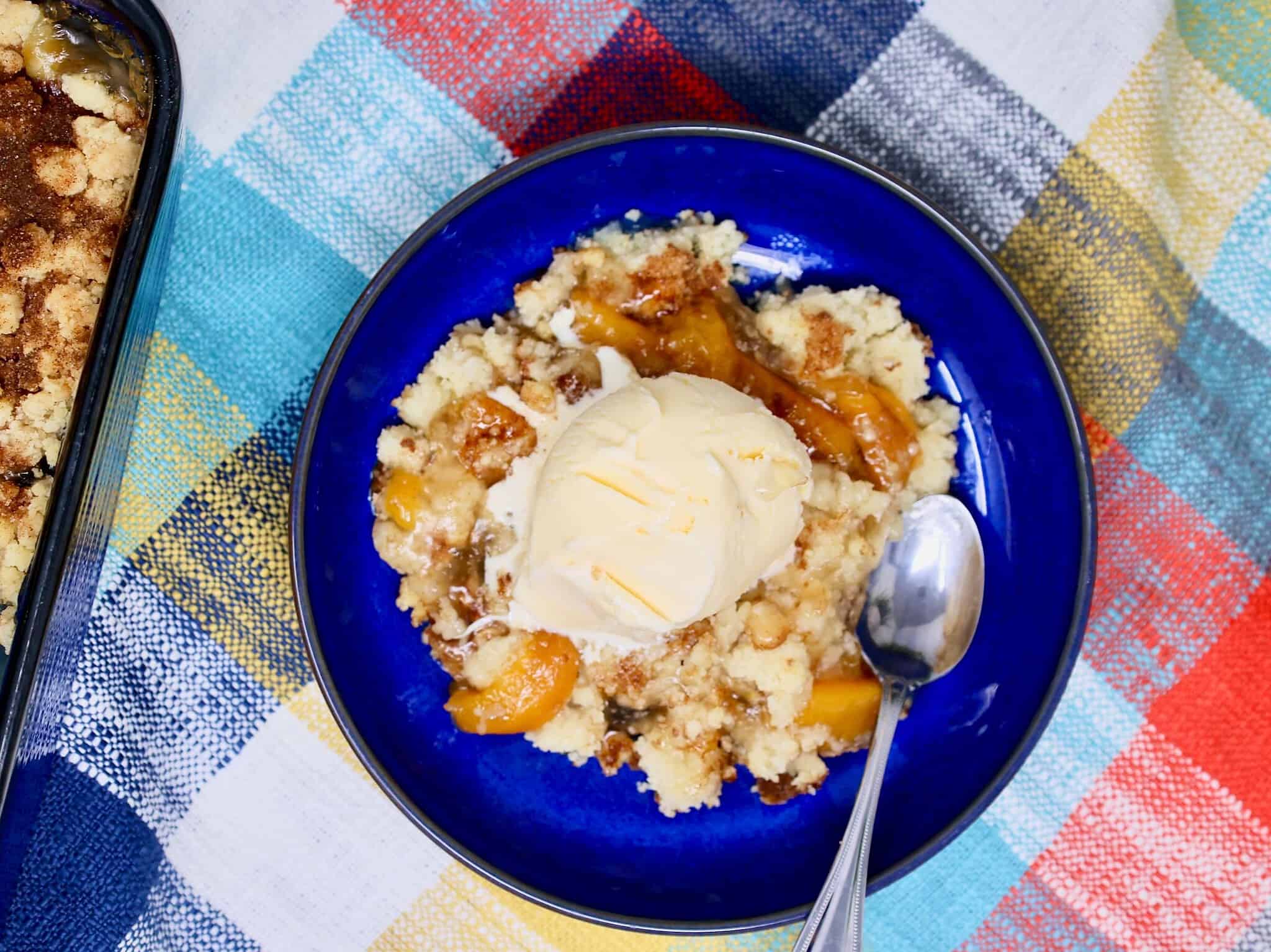 Warm peach crisp topped with a scoop of vanilla ice cream