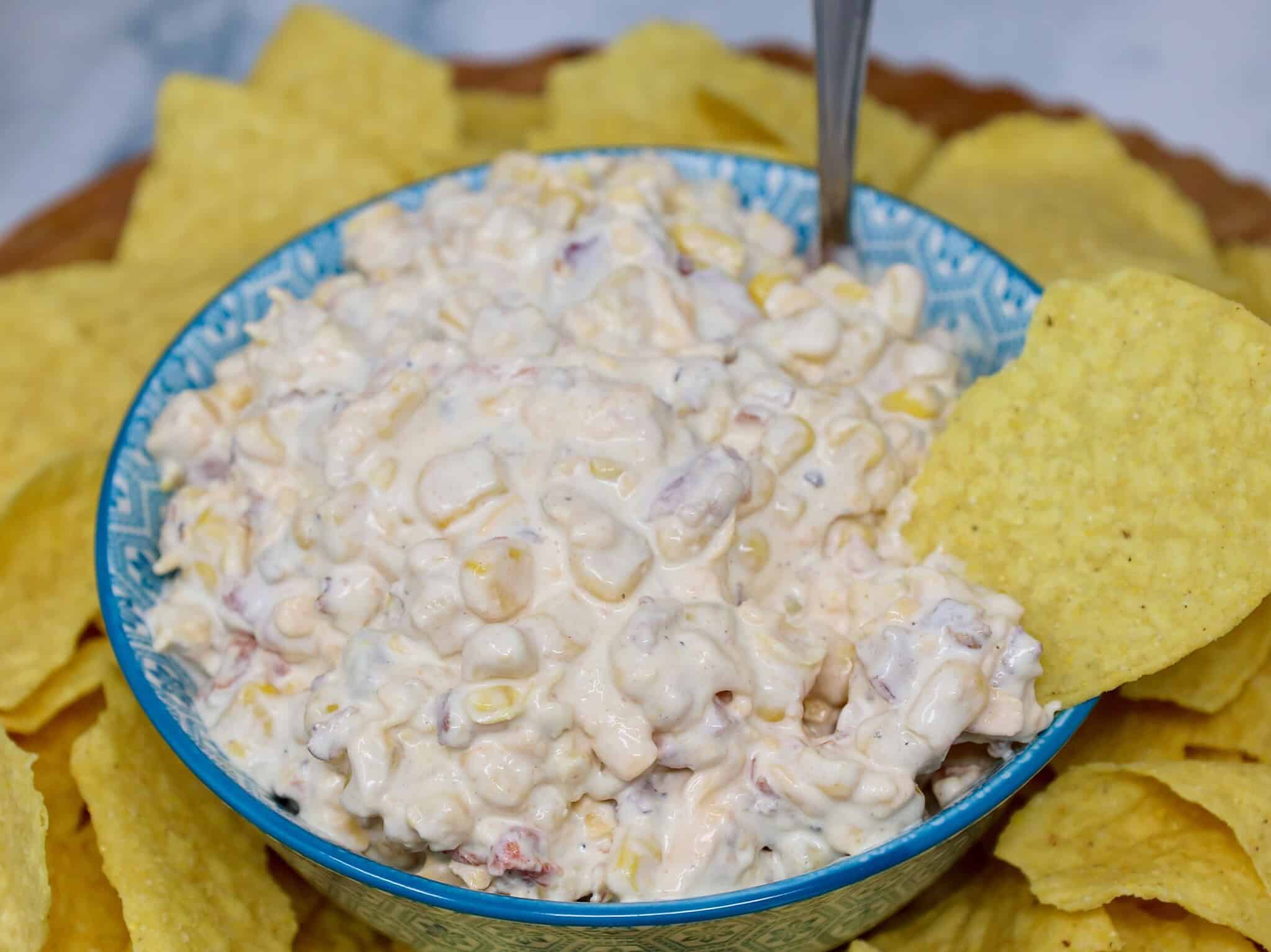 Bacon cheddar corn dip garnished with extra bacon, cheese, and green onions before serving