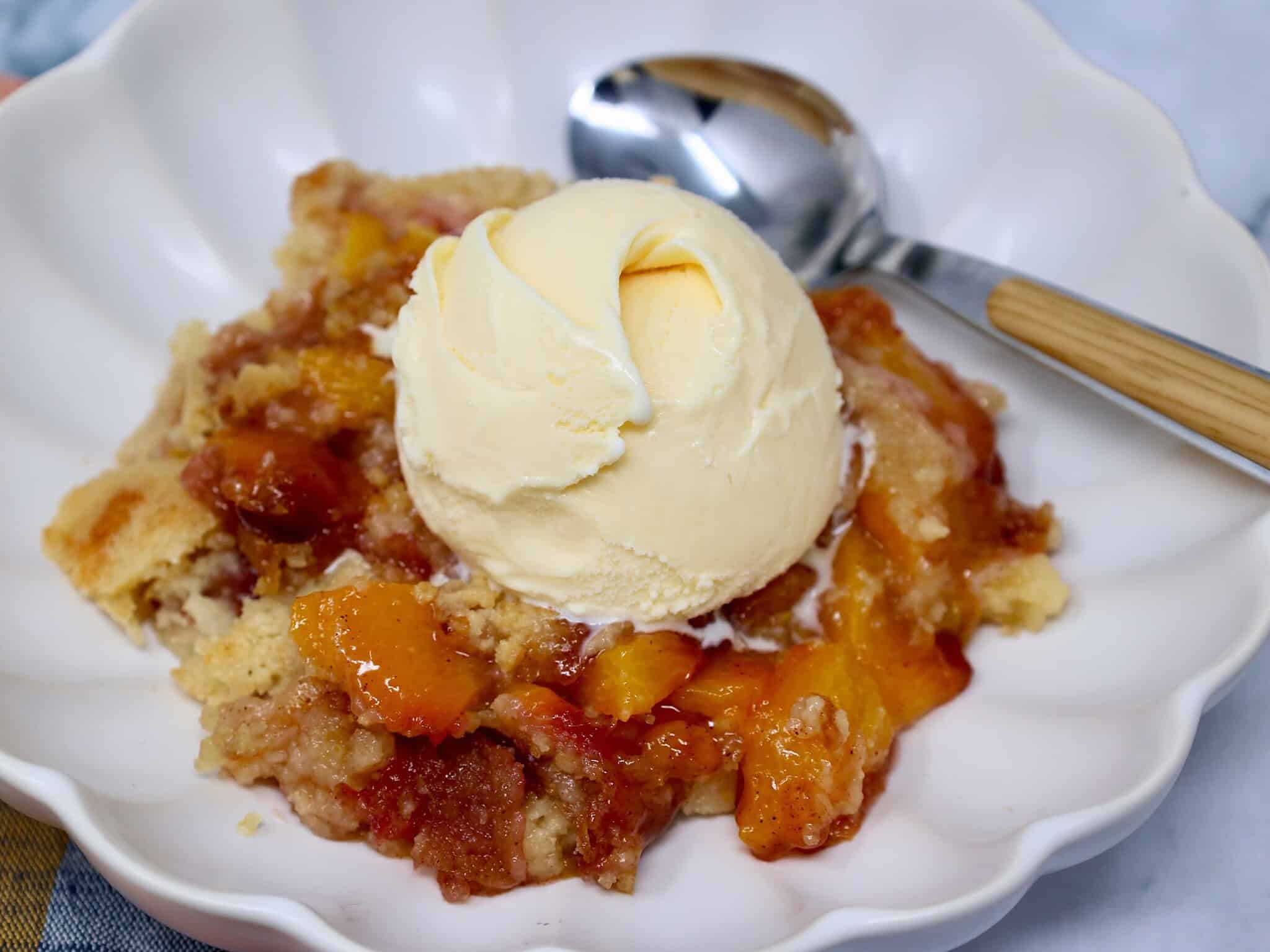 Serving of Fresh Peach Dump Cake topped with vanilla ice cream