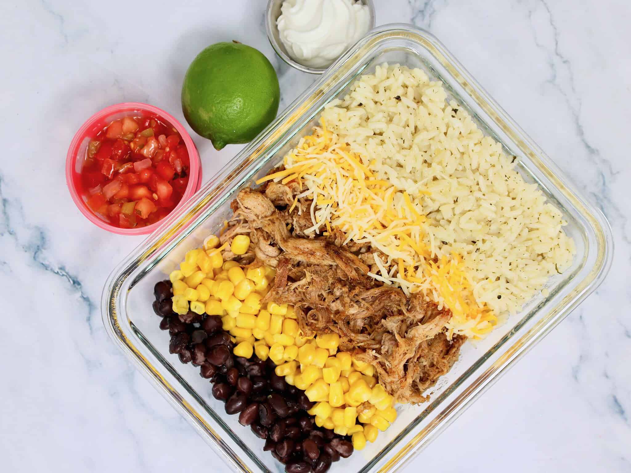 Pulled pork rice bowl served with pico de gallo, sour cream, cilantro, and a lime