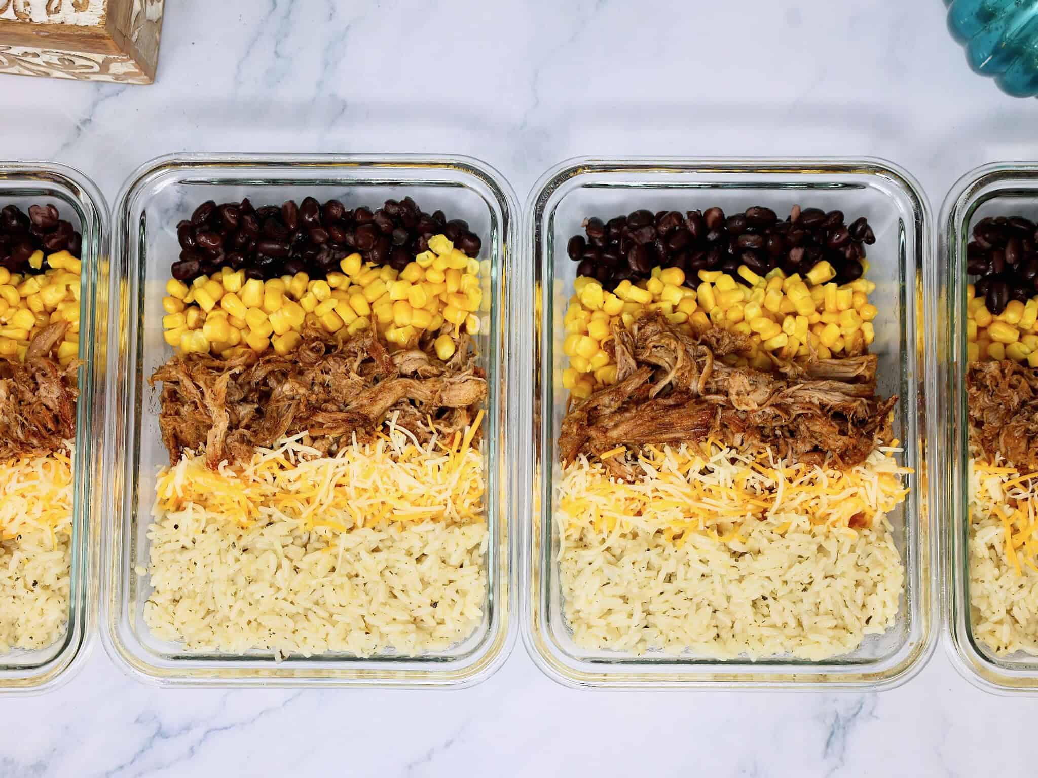 Easy meal prep burrito bowls with seasoned pulled pork, rice, beans, corn, and cheese
