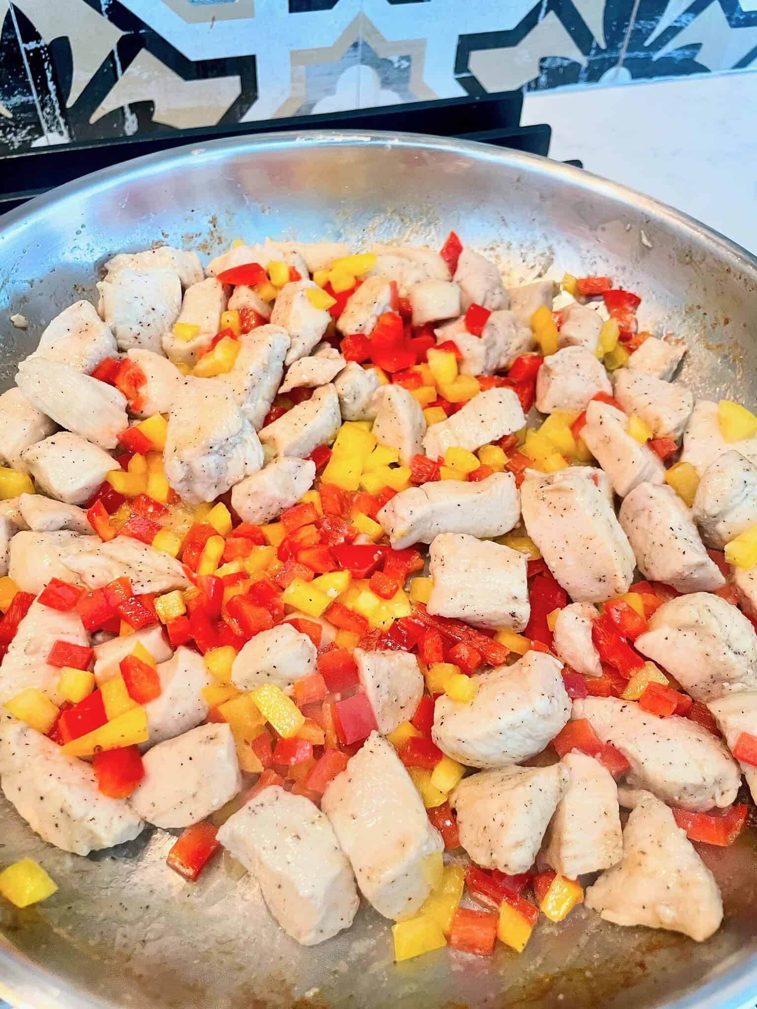Close up of chicken tikka masala with peas and diced bell peppers