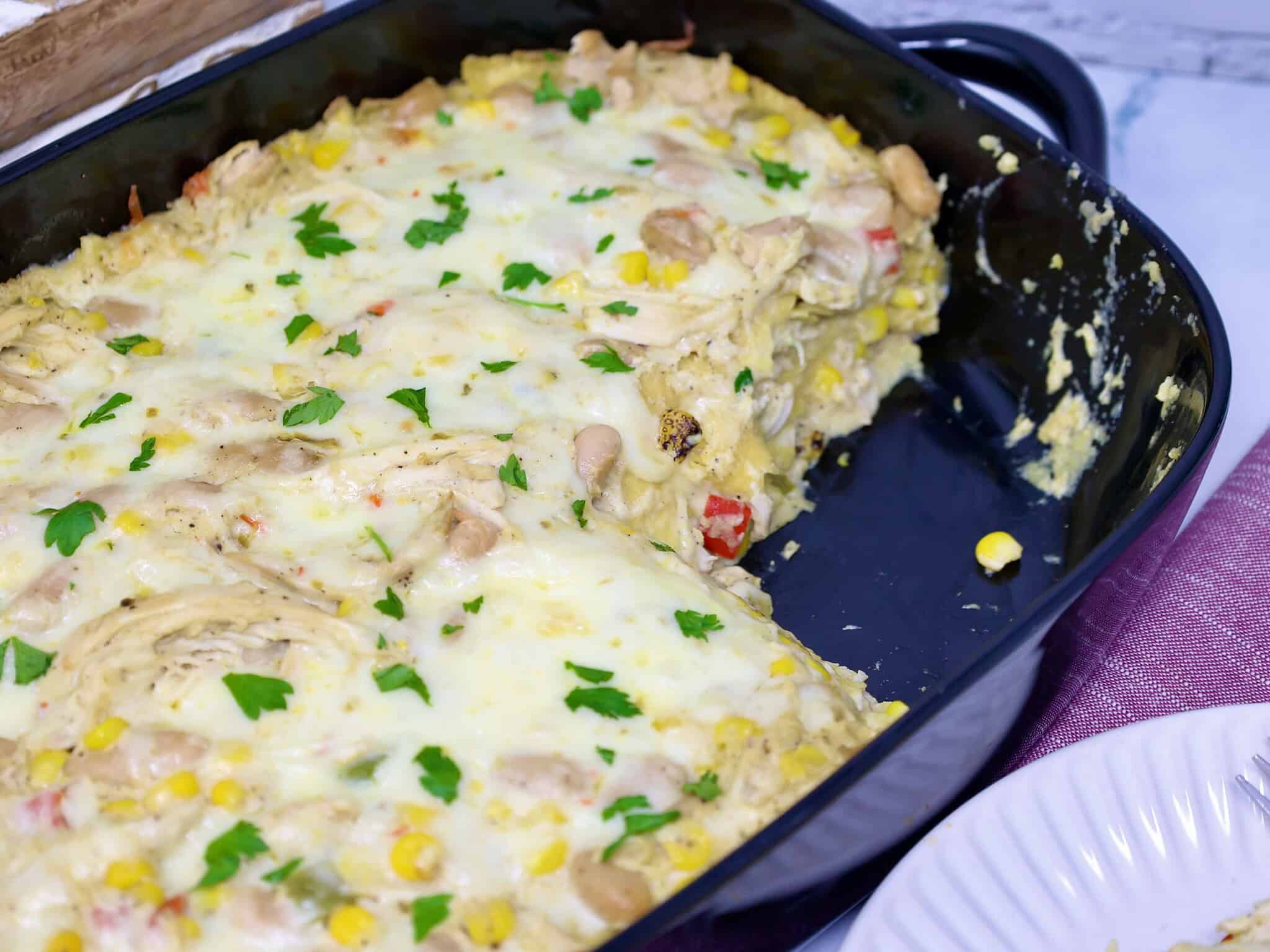 layered mexican-style casserole missing a serving of creamy chicken enchilada casserole with corn and white beans