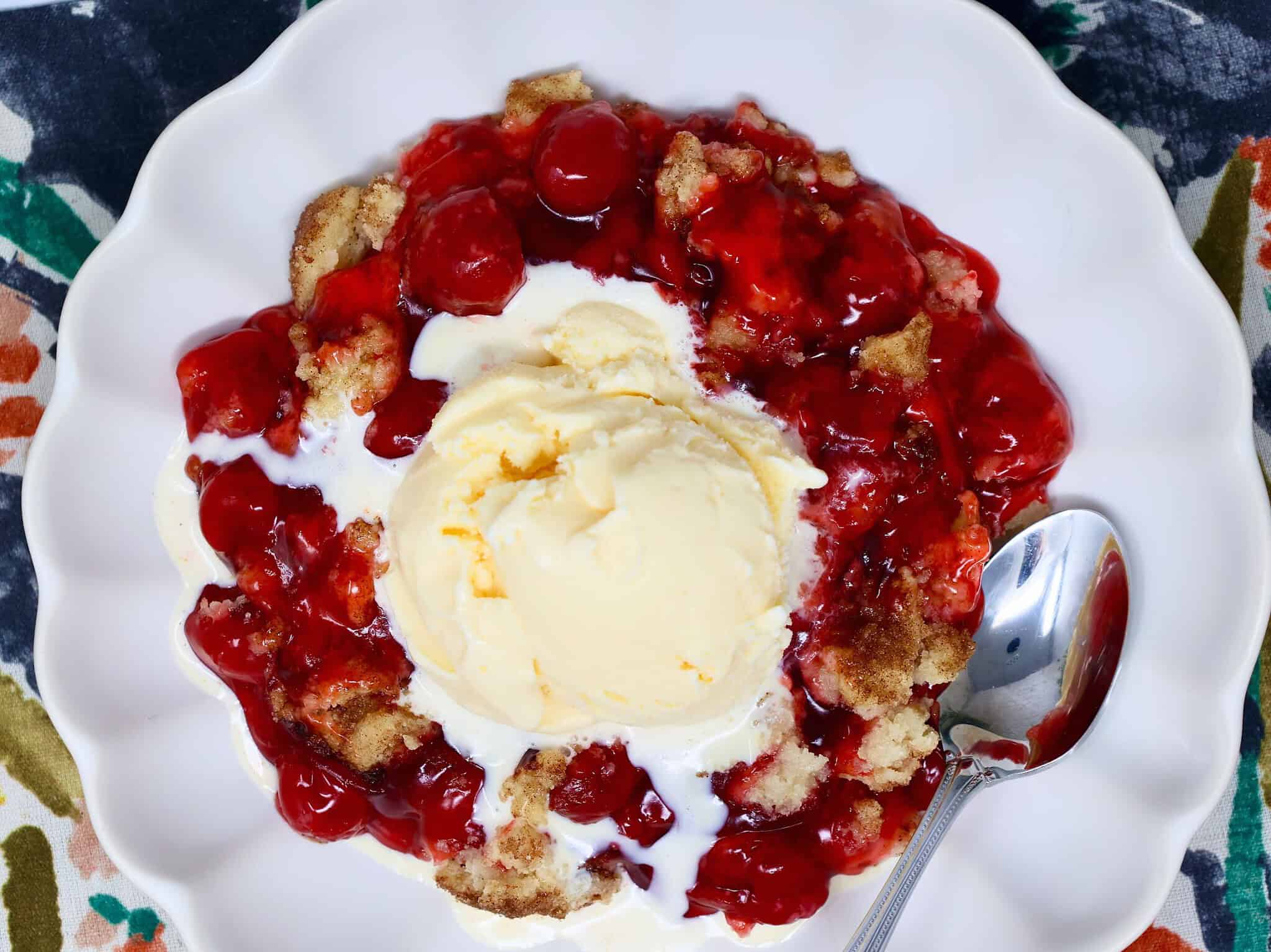 Spoonful of easy snickerdoodle cherry crisp showing soft cherry filling and crisp cinnamon cookie topping.