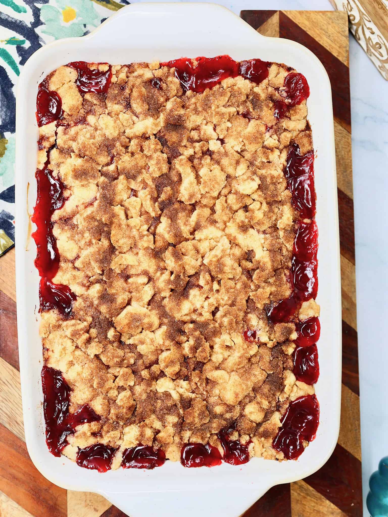Homemade snickerdoodle cherry crisp baked in a 9x13-inch dish with a golden brown cookie crumble topping.